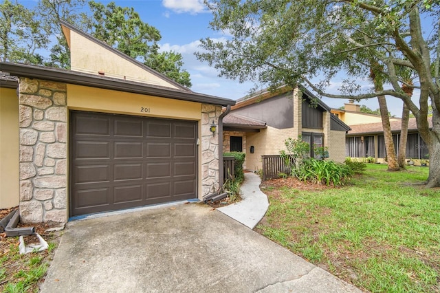 2101 Sunset Point Rd Unit 201, Clearwater, FL 33765 - mid-century modern home featuring concrete driveway, stone siding, a garage, a front lawn, and stucco siding
