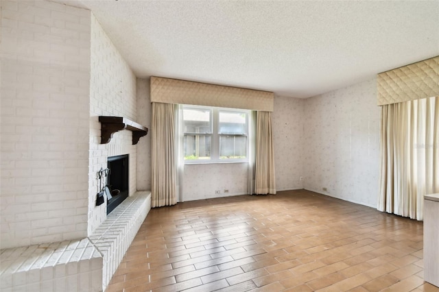 2101 Sunset Point Rd Unit 201, Clearwater, FL 33765 - unfurnished living room with a textured ceiling, a fireplace, wallpapered walls, and brick patterned floors