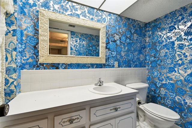 2101 Sunset Point Rd Unit 201, Clearwater, FL 33765 - bathroom with wallpapered walls, vanity, a wainscoted wall, and a textured ceiling