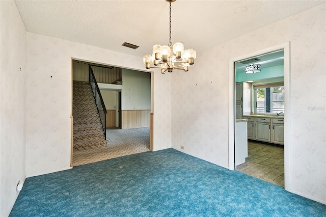 2101 Sunset Point Rd Unit 201, Clearwater, FL 33765 - carpeted spare room with a chandelier, a textured ceiling, stairway, and wallpapered walls