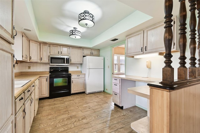 2101 Sunset Point Rd Unit 201, Clearwater, FL 33765 - kitchen featuring freestanding refrigerator, black range with electric cooktop, stainless steel microwave, light countertops, and a raised ceiling