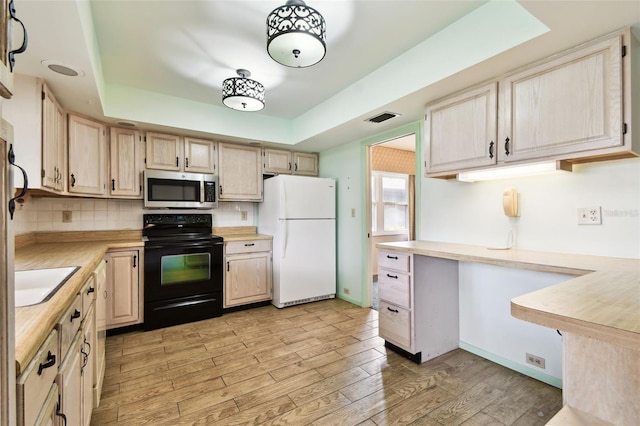 2101 Sunset Point Rd Unit 201, Clearwater, FL 33765 - kitchen featuring freestanding refrigerator, stainless steel microwave, black electric range, light countertops, and light wood-type flooring