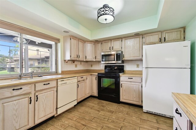 2101 Sunset Point Rd Unit 201, Clearwater, FL 33765 - kitchen featuring white appliances, light countertops, decorative backsplash, light brown cabinetry, and light wood-type flooring