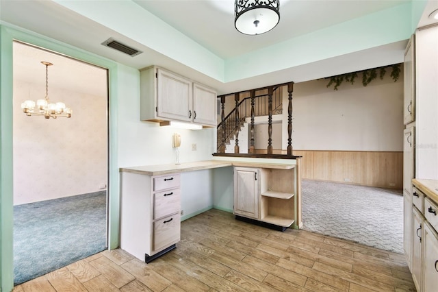 2101 Sunset Point Rd Unit 201, Clearwater, FL 33765 - kitchen with light wood-style flooring, light countertops, light colored carpet, a wainscoted wall, and a chandelier