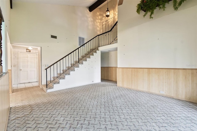 2101 Sunset Point Rd Unit 201, Clearwater, FL 33765 - foyer entrance with a towering ceiling, stairway, a wainscoted wall, carpet, and beam ceiling