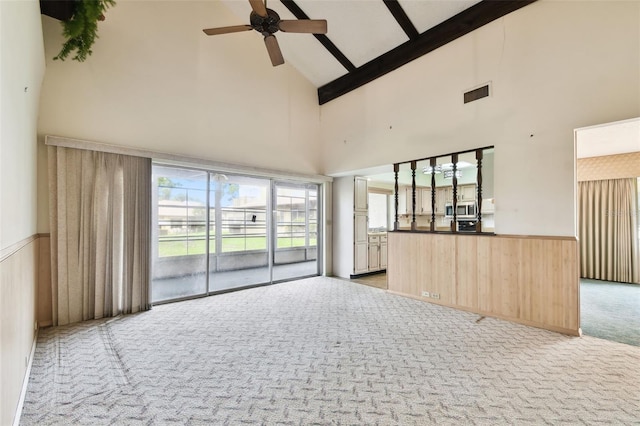 2101 Sunset Point Rd Unit 201, Clearwater, FL 33765 - unfurnished living room with high vaulted ceiling, light colored carpet, ceiling fan, wainscoting, and wood walls