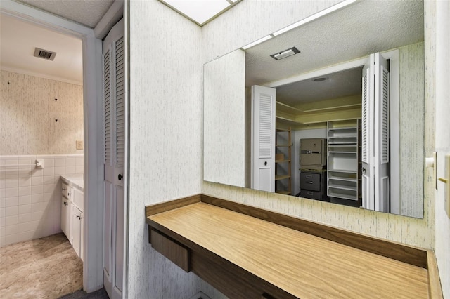 2101 Sunset Point Rd Unit 201, Clearwater, FL 33765 - bathroom with vanity, wallpapered walls, tile walls, and a wainscoted wall