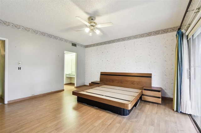 2101 Sunset Point Rd Unit 201, Clearwater, FL 33765 - bedroom featuring wood finished floors, a textured ceiling, a ceiling fan, and ensuite bathroom