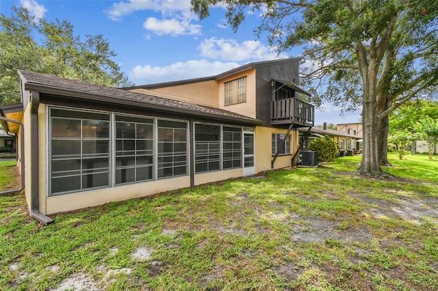 2101 Sunset Point Rd Unit 201, Clearwater, FL 33765 - back of house featuring stucco siding, a balcony, a lawn, and a shingled roof
