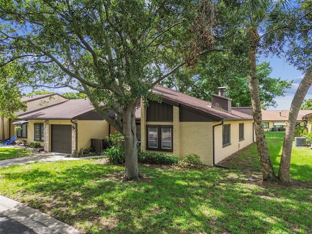 2101 Sunset Point Rd Unit 201, Clearwater, FL 33765 - mid-century home featuring a garage, a front yard, brick siding, a chimney, and driveway