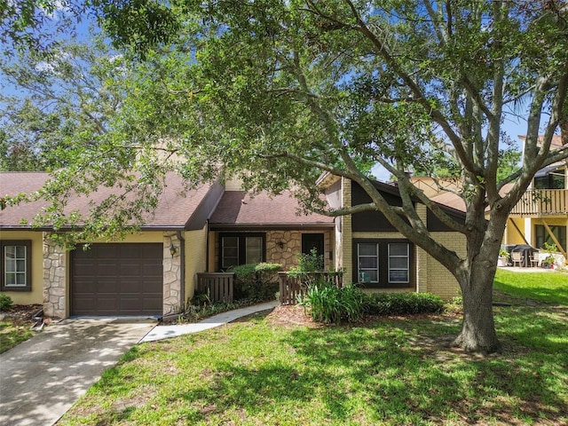 2101 Sunset Point Rd Unit 201, Clearwater, FL 33765 - view of front facade featuring stone siding, a garage, driveway, a front lawn, and a shingled roof