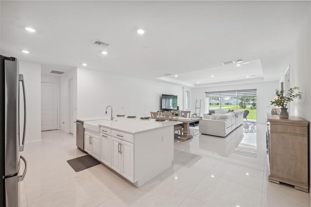 33466 Landsman Loop, Wesley Chapel, FL 33543 - kitchen with stainless steel appliances, open floor plan, a raised ceiling, white cabinetry, and light countertops