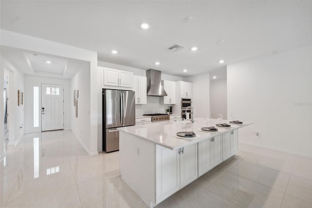 33466 Landsman Loop, Wesley Chapel, FL 33543 - kitchen featuring stainless steel appliances, wall chimney range hood, white cabinetry, recessed lighting, and a large island with sink