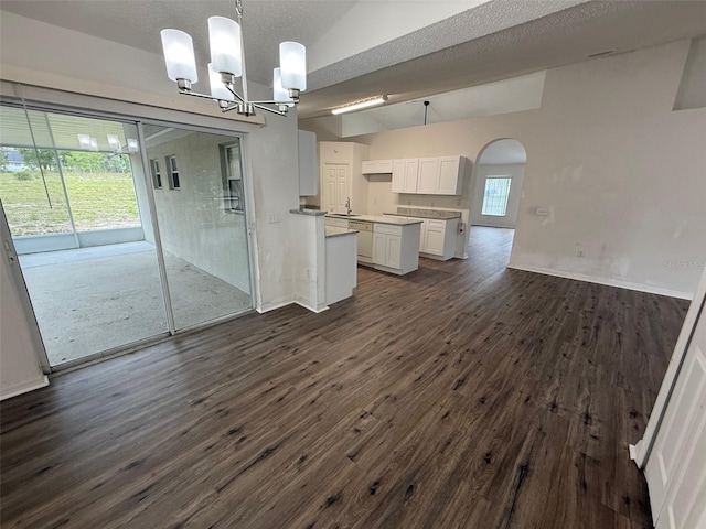 11308 Mahopac Rd, Weeki Wachee, FL 34614 - kitchen with vaulted ceiling, white cabinetry, a chandelier, dark wood-type flooring, and arched walkways