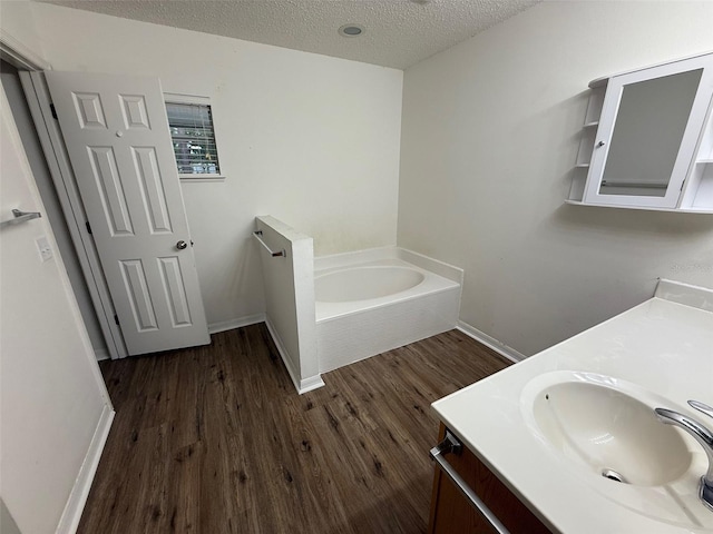 11308 Mahopac Rd, Weeki Wachee, FL 34614 - bathroom featuring wood finished floors, a textured ceiling, vanity, and a garden tub