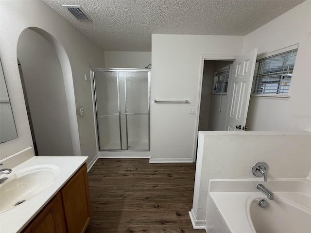11308 Mahopac Rd, Weeki Wachee, FL 34614 - full bathroom featuring wood finished floors, a shower stall, a bath, vanity, and a textured ceiling