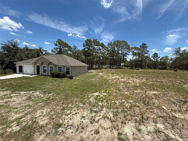 11308 Mahopac Rd, Weeki Wachee, FL 34614 - view of property exterior with a garage, driveway, a yard, stucco siding, and view of wooded area
