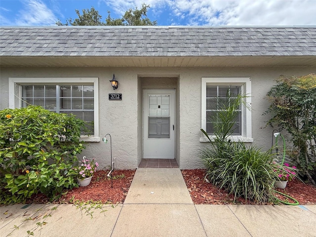 3712 Trophy Blvd Unit 3712, New Port Richey, FL 34655 - view of exterior entry with roof with shingles, stucco siding, and mansard roof