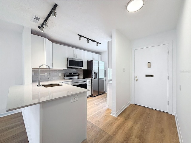 3712 Trophy Blvd Unit 3712, New Port Richey, FL 34655 - kitchen featuring appliances with stainless steel finishes, track lighting, decorative backsplash, light wood finished floors, and white cabinetry