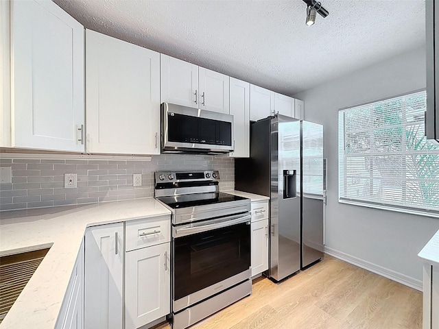 3712 Trophy Blvd Unit 3712, New Port Richey, FL 34655 - kitchen with stainless steel appliances, a textured ceiling, backsplash, light wood finished floors, and white cabinets