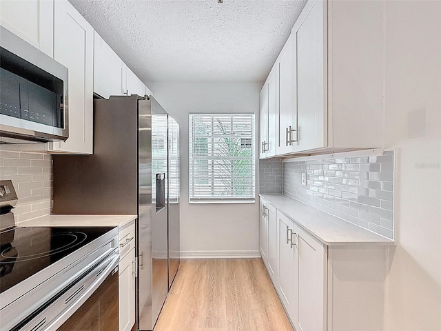 3712 Trophy Blvd Unit 3712, New Port Richey, FL 34655 - kitchen with stainless steel appliances, light countertops, white cabinets, a textured ceiling, and light wood-style flooring