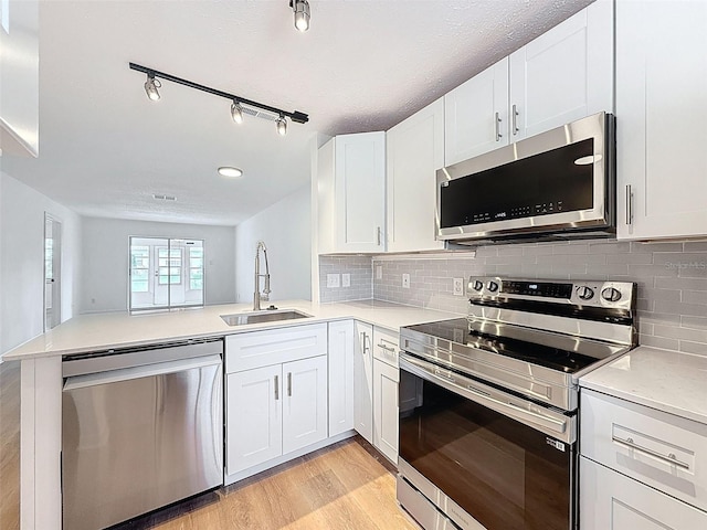 3712 Trophy Blvd Unit 3712, New Port Richey, FL 34655 - kitchen with stainless steel appliances, a peninsula, light wood-type flooring, light countertops, and white cabinetry