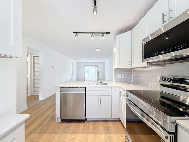 3712 Trophy Blvd Unit 3712, New Port Richey, FL 34655 - kitchen featuring stainless steel appliances, track lighting, light wood-type flooring, backsplash, and white cabinetry