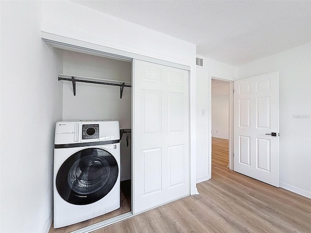 3712 Trophy Blvd Unit 3712, New Port Richey, FL 34655 - laundry area featuring washer / dryer, light wood finished floors, and a textured ceiling