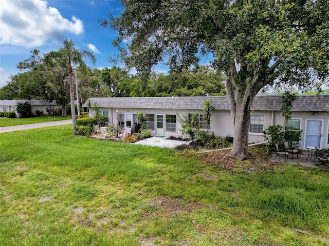 3712 Trophy Blvd Unit 3712, New Port Richey, FL 34655 - ranch-style home with a front yard, stucco siding, roof with shingles, and a patio area