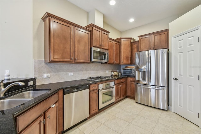 20820 Amanda Oak Ct, Land O Lakes, FL 34638 - kitchen with stainless steel appliances, dark stone countertops, light tile patterned flooring, brown cabinets, and tasteful backsplash
