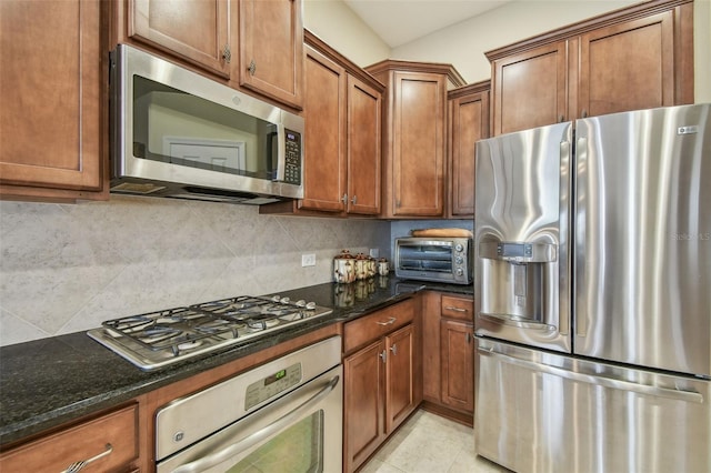 20820 Amanda Oak Ct, Land O Lakes, FL 34638 - kitchen featuring stainless steel appliances, brown cabinetry, decorative backsplash, and dark stone countertops