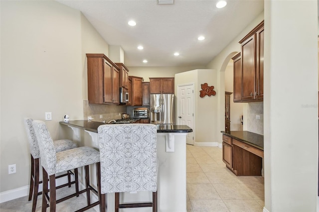 20820 Amanda Oak Ct, Land O Lakes, FL 34638 - kitchen with appliances with stainless steel finishes, a peninsula, a kitchen breakfast bar, tasteful backsplash, and arched walkways