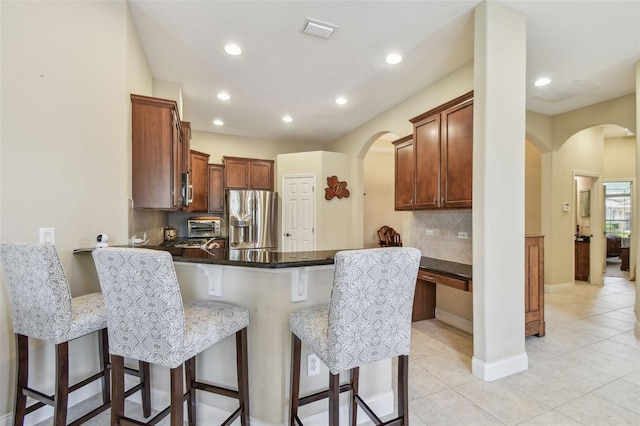 20820 Amanda Oak Ct, Land O Lakes, FL 34638 - kitchen with stainless steel fridge, arched walkways, a breakfast bar, a peninsula, and tasteful backsplash