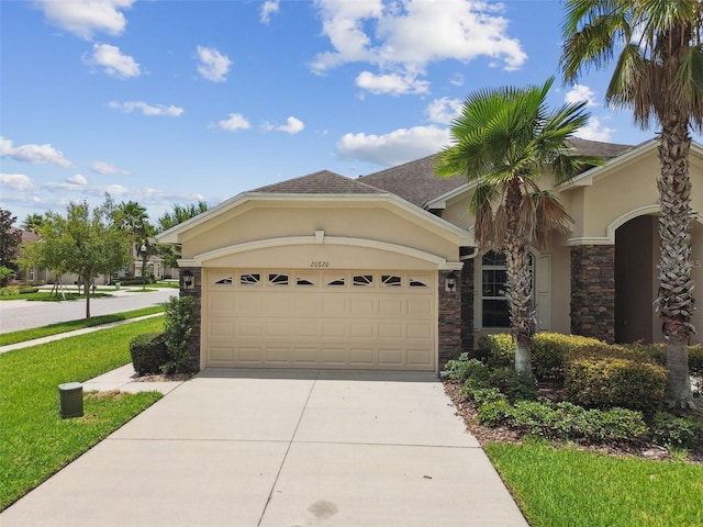 20820 Amanda Oak Ct, Land O Lakes, FL 34638 - view of front facade featuring concrete driveway, an attached garage, stucco siding, stone siding, and a front lawn