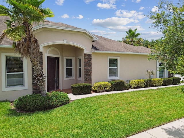 20820 Amanda Oak Ct, Land O Lakes, FL 34638 - view of front of house with stucco siding, stone siding, a front yard, and roof with shingles