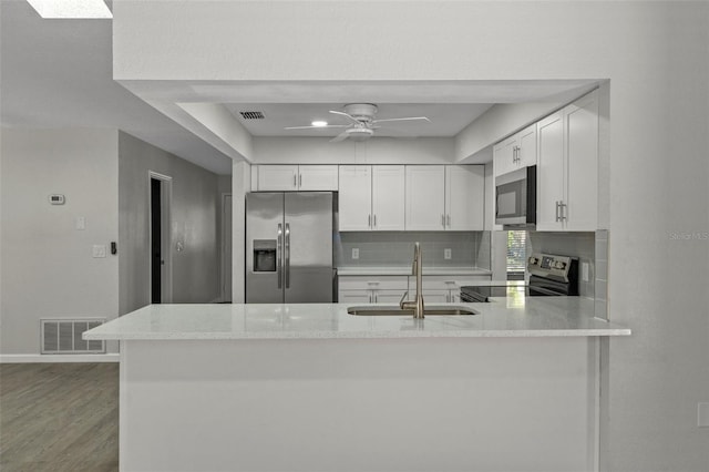 2152 Danforth Rd, Spring Hill, FL 34608 - kitchen with stainless steel appliances, backsplash, white cabinetry, and a peninsula