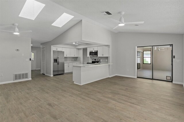 2152 Danforth Rd, Spring Hill, FL 34608 - unfurnished living room with a ceiling fan, a skylight, light wood finished floors, high vaulted ceiling, and a textured ceiling