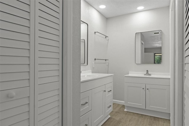 2152 Danforth Rd, Spring Hill, FL 34608 - bathroom with two vanities, wood finished floors, a textured ceiling, and recessed lighting