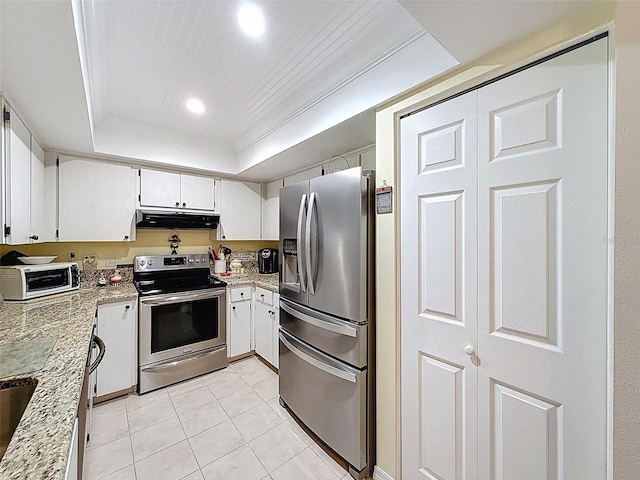 8130 Bugle Ct Unit 3, Port Richey, FL 34668 - kitchen with appliances with stainless steel finishes, under cabinet range hood, light tile patterned floors, a tray ceiling, and light stone counters