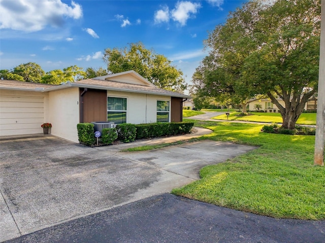 8130 Bugle Ct Unit 3, Port Richey, FL 34668 - view of side of home with a lawn, stucco siding, concrete driveway, and a garage