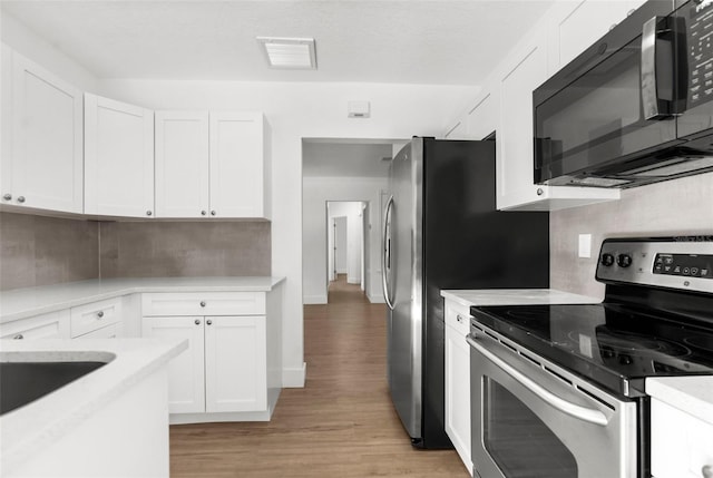 7192 Catalina St, Spring Hill, FL 34606 - kitchen with black microwave, stainless steel electric stove, light wood-style floors, and white cabinetry