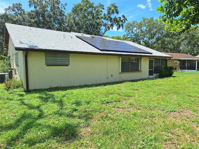 4420 Sawgrass Blvd, New Port Richey, FL 34653 - back of property featuring roof mounted solar panels, a yard, stucco siding, roof with shingles, and a sunroom