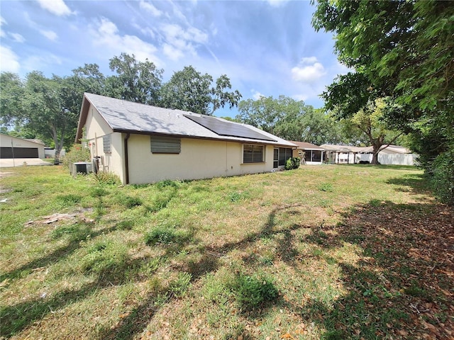 4420 Sawgrass Blvd, New Port Richey, FL 34653 - back of property with solar panels, stucco siding, and a yard