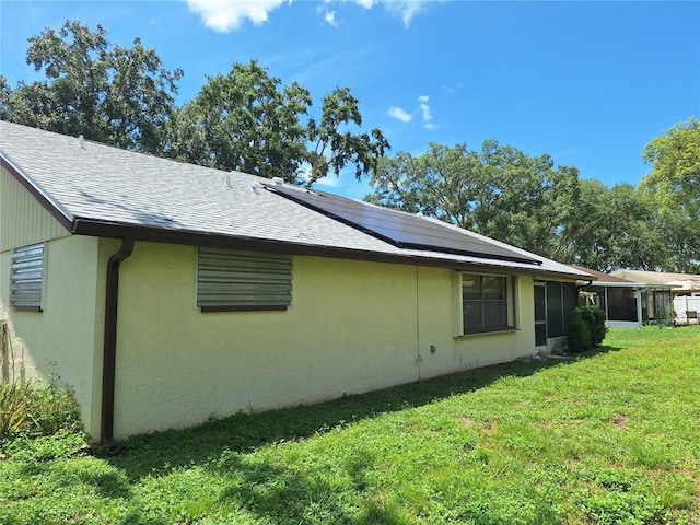 4420 Sawgrass Blvd, New Port Richey, FL 34653 - view of side of property with solar panels, a yard, a sunroom, a shingled roof, and stucco siding