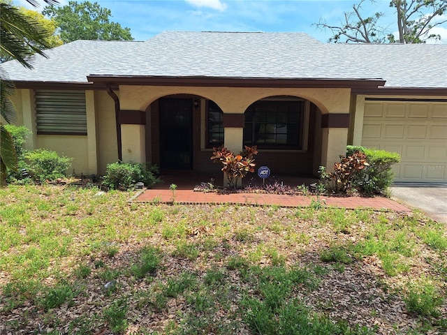 4420 Sawgrass Blvd, New Port Richey, FL 34653 - view of front of house featuring a garage, stucco siding, a shingled roof, and covered porch