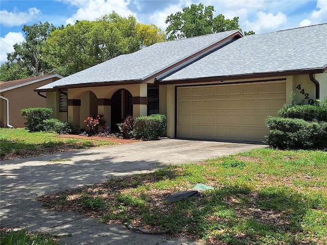 4420 Sawgrass Blvd, New Port Richey, FL 34653 - view of front of house with an attached garage, concrete driveway, stucco siding, and a shingled roof