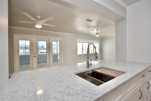 5339 Bowline Bnd, New Port Richey, FL 34652 - kitchen with ceiling fan, light stone countertops, crown molding, white cabinets, and healthy amount of natural light