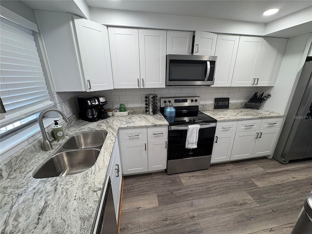 5555 Gulf Blvd Unit 315, St Pete Beach, FL 33706 - kitchen with appliances with stainless steel finishes, dark wood finished floors, backsplash, white cabinets, and light stone counters