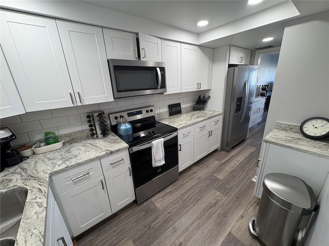 5555 Gulf Blvd Unit 315, St Pete Beach, FL 33706 - kitchen with stainless steel appliances, white cabinets, dark wood-style floors, backsplash, and recessed lighting