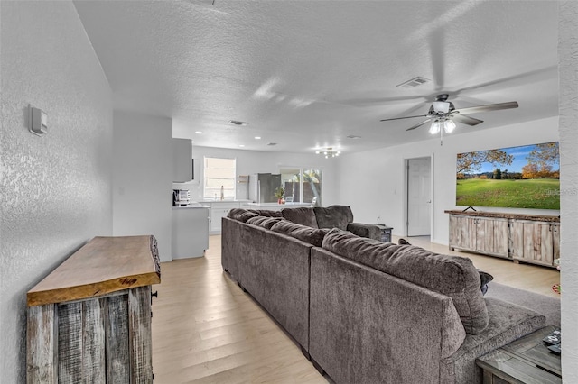 15950 Adobe Dr, Hudson, FL 34667 - living room featuring light wood-style floors, a ceiling fan, a textured wall, and a textured ceiling